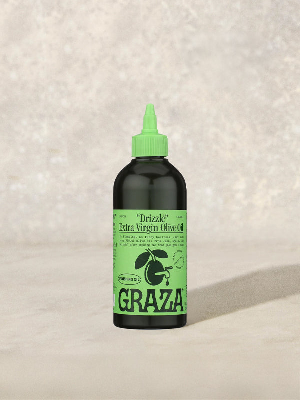 A sleek bottle of Graza Baby Drizzle olive oil, featuring a vibrant green label and a modern, ergonomic design. The olive oil is known for its rich, smooth flavor, perfect for drizzling over dishes or using as a finishing touch in cooking.